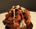 A melt in your mouth chocolate cupcake with chocolate icing, white chocolate drizzled on top with chocolate chips. 